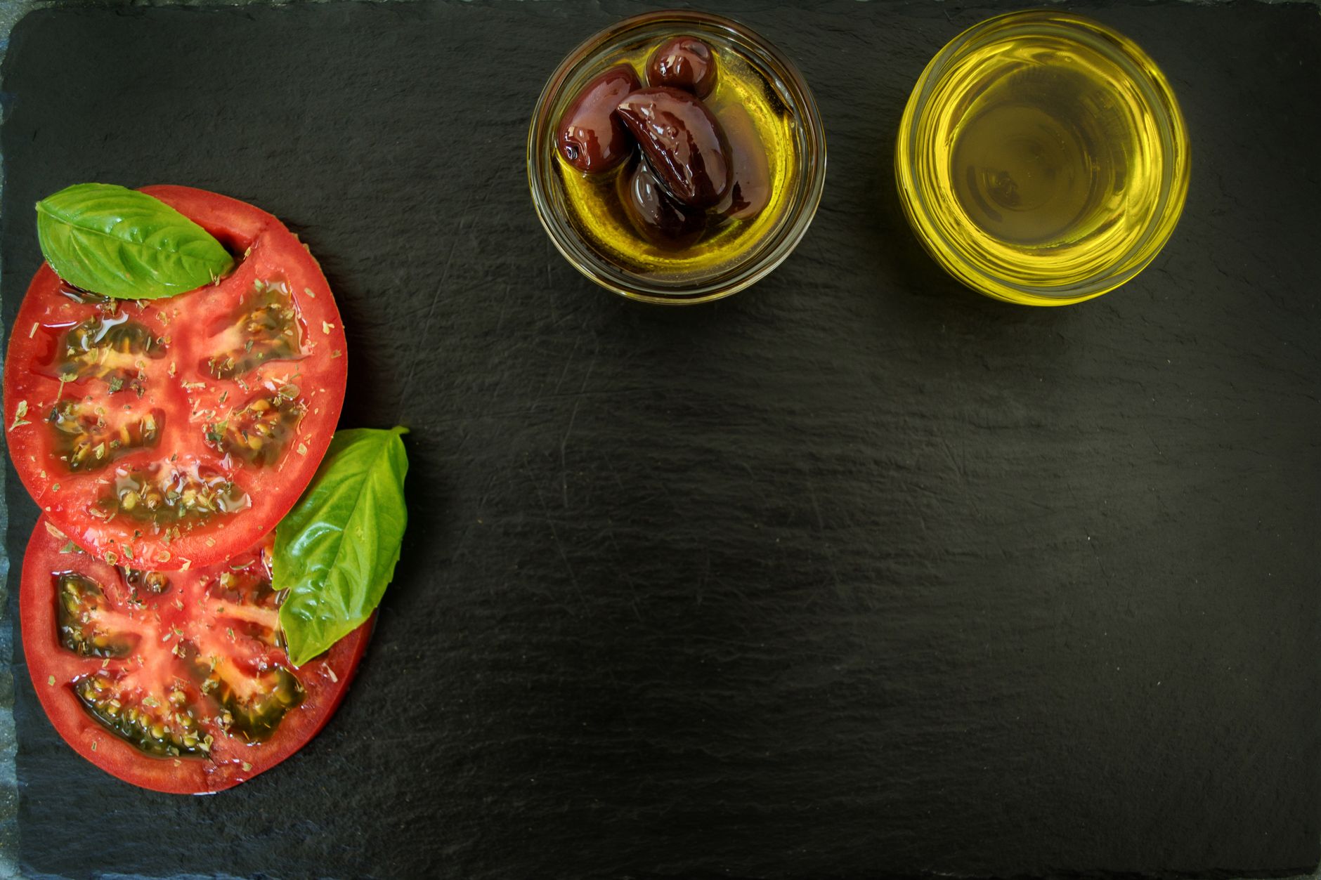 Fresh rustic bread, extra virgin olive oil, and organic tomatoes on slate board
