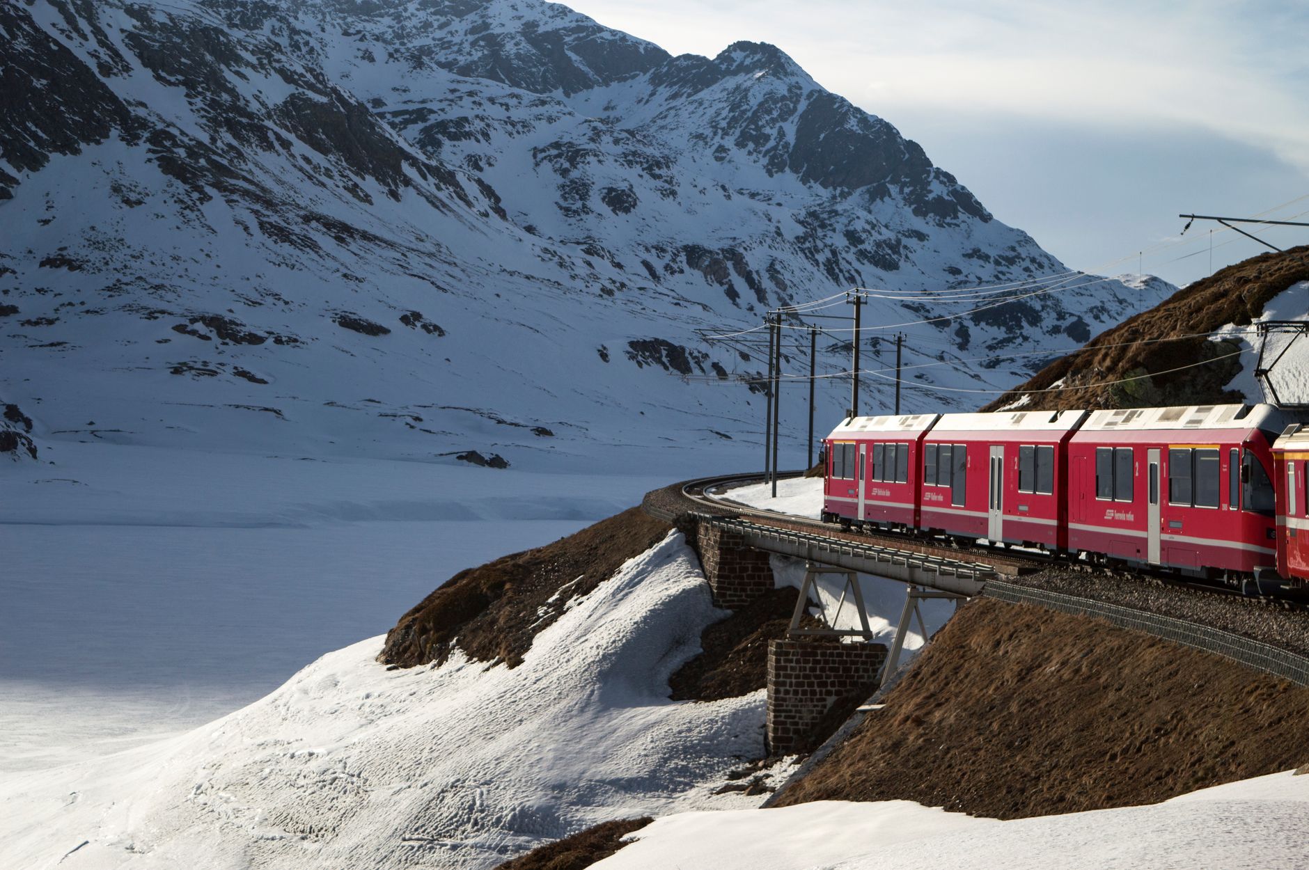Vintage train traveling slowly past snow capped mountain peaks
